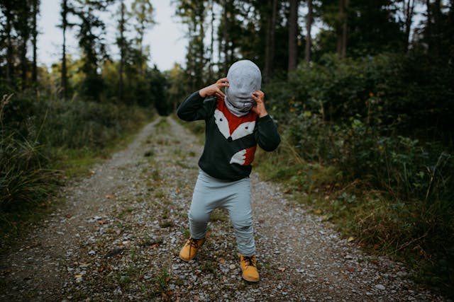 A scary kid wearing a mask in dark woods
